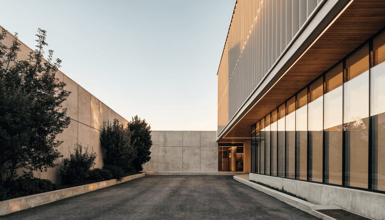 Modern luxury short-term rental property exterior at golden hour: concrete, glass, and wood architecture against warm evening light.